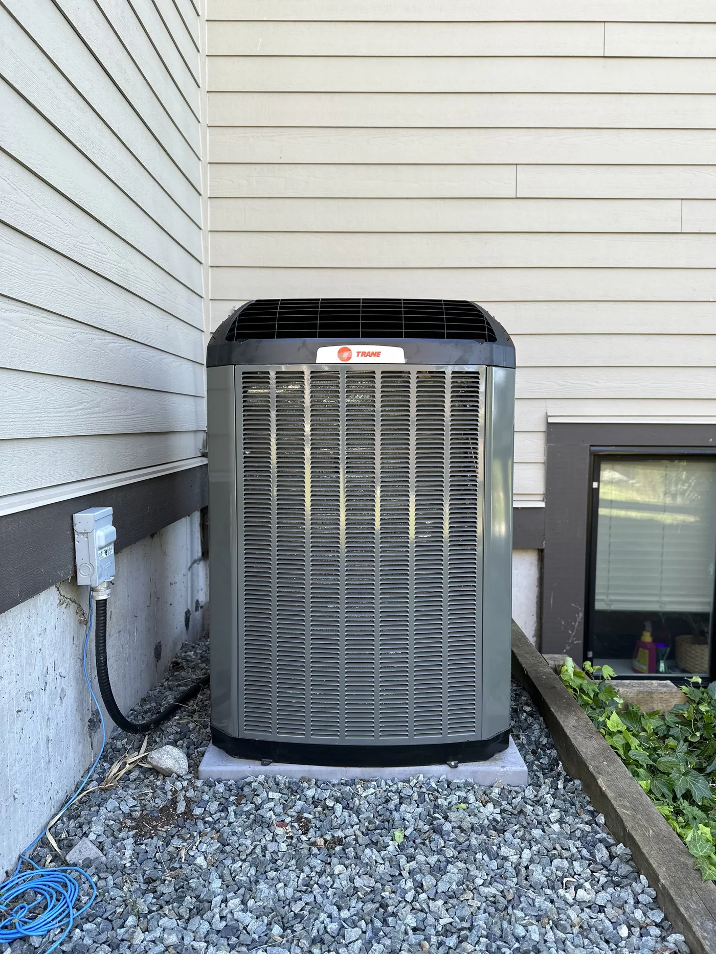Trane unit on a gravel bed, clear of the siding